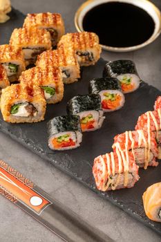 Sushi set of various products on a black stone plate. Blur background and selective focus