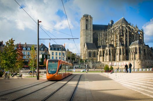 LE MANS, FRANCE - OCTOBER 08, 2017: Roman cathedral of Saint Julien with an orange tram at a Le mans Sarthe, Pays de la Loire, France