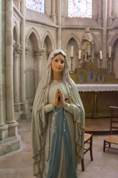 A statue of the Virgin Mary holding a rosary and praying