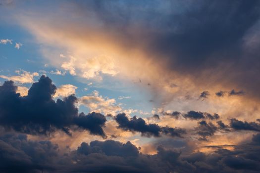 Cumulus clouds on evening sky backlit with sunset. Captured with 70mm lens on 35mm full-frame sensor camera.
