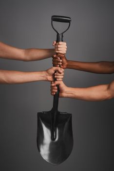 Lets dig in. Studio shot of unidentifiable hands holding on to a shovel against a gray background