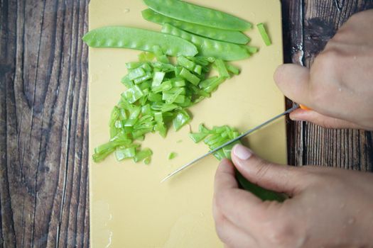 women cutting Holland beans on the cutting board.