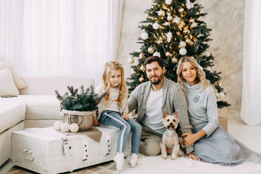 Happy family: mom, dad and pet. Family in a bright New Year's interior with a Christmas tree.