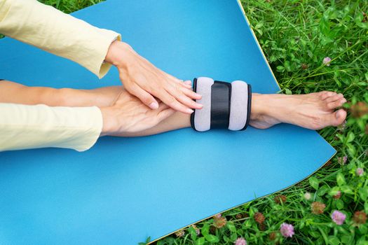 Sports girl doing exercises and stretching in nature outdoors on a blurred background. A woman is doing yoga in the park, sitting on the grass on a yoga mat