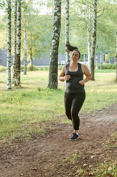 A charming brunette woman plus-size body positive practices sports in nature.