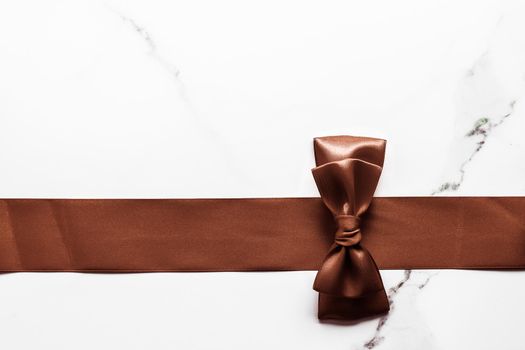 Holiday gift, decoration and sale promotion concept - Chocolate brown silk ribbon on marble background, flatlay