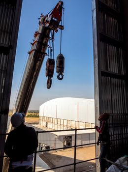 Hoist of crane at the window of industrial plant