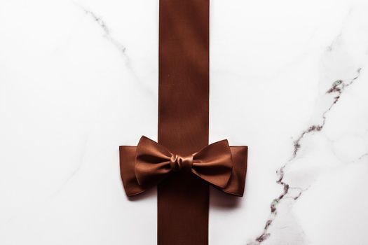 Holiday gift, decoration and sale promotion concept - Chocolate brown silk ribbon on marble background, flatlay