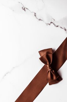 Holiday gift, decoration and sale promotion concept - Chocolate brown silk ribbon on marble background, flatlay