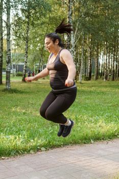 A charming brunette woman plus-size body positive practices sports in nature.