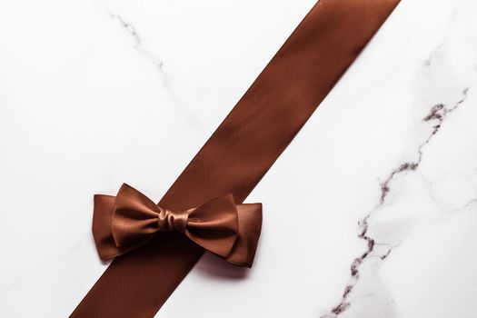 Holiday gift, decoration and sale promotion concept - Chocolate brown silk ribbon on marble background, flatlay