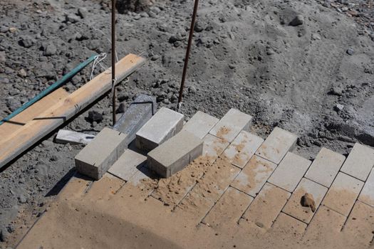 Pavement repair and laying of paving slabs on the walkway, stacked tile cubes on the background. Laying paving slabs in the pedestrian zone of the city, sand filling. Road tiles and curbs