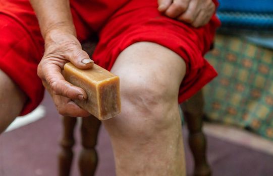 Grandmother treats her knees with soap. Selective focus. Woman.
