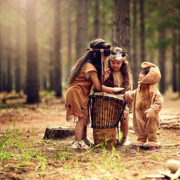 Three little drummers. three little girls banging a drum while playing dressup in the woods