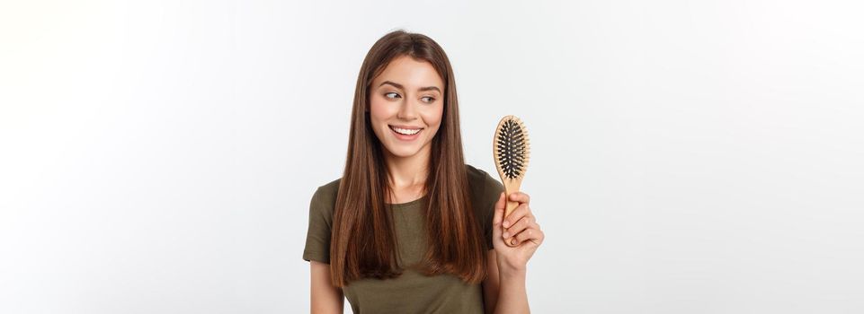 Happy young woman combing her long healthy hair on white background