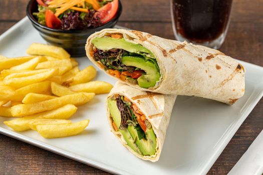 Vegetarian wrap french fries with vegetables on a white porcelain plate