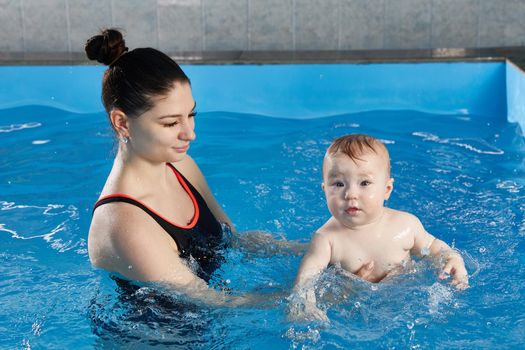 Little child learning to swim in pool with a teacher