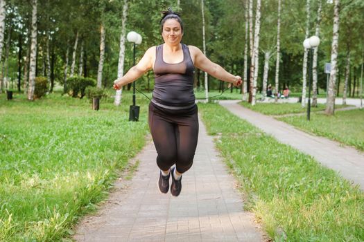 A charming brunette woman plus-size body positive practices sports in nature.