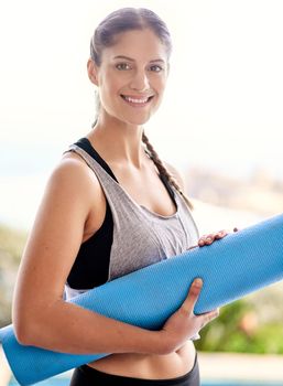 Im headed to yoga class. Portrait of an attractive young woman carrying her yoga mat to class