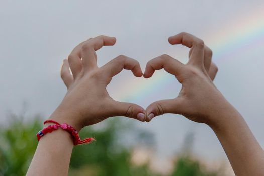 The child makes a heart with his hands rainbow, . Selective focus. Kid.