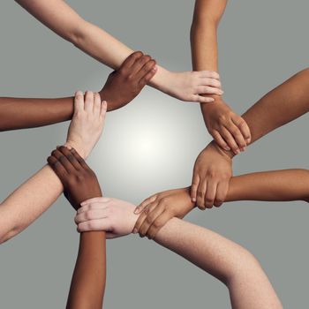 United together for a common cause. a group of hands holding on to each other at the wrist against a grey background