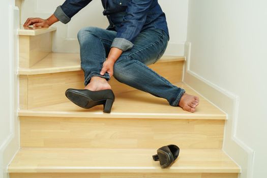 Asian business woman pain ankle, foot with leg cramp and fall down the stairs because slippery surfaces in office.
