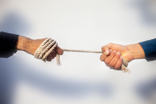 Close up shot of two male hand playing tug of war over blurred background.