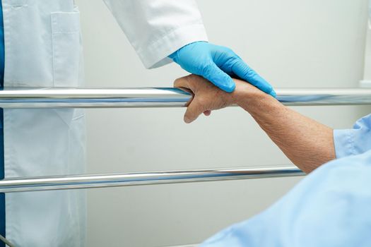 Asian elder senior woman patient holding bed rail while lie down with hope waiting her family in hospital.