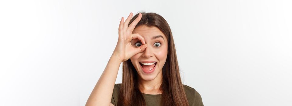 Close up portrait of cheerful, cute, stylish,attractive, trendy girl making binoculars with fingers, isolated on grey background, having good mood.