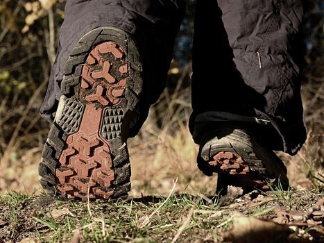 Female walking in high trekking boots on the background of leaves and trees