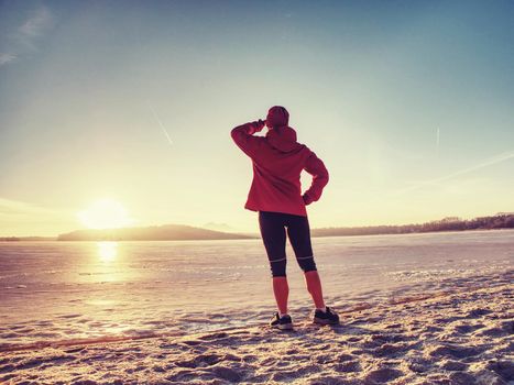 Caucasian girl with slim fit body doing stretching exercises before jogging workout on winter beach against blurred ocean 