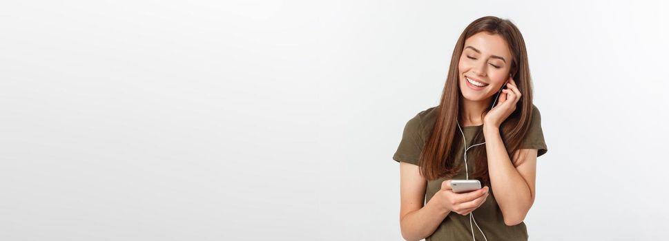 Portrait of a cheerful cute woman listening music in headphones and dancing isolated on a white background