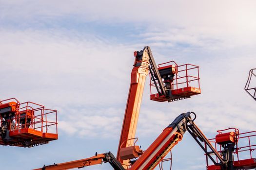 Articulated boom lift. Aerial platform lift. Telescopic boom lift against blue sky. Mobile construction crane for rent and sale. Maintenance and repair hydraulic boom lift service. Crane dealership.