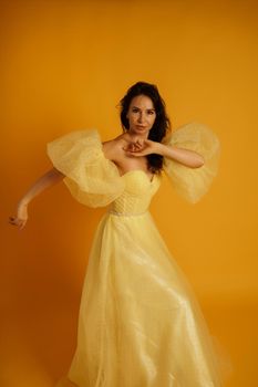 Portrait of a beautiful middle-aged woman in a yellow dress, her hair pulled up against a yellow background.