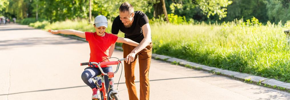 happy family father teaches child daughter to ride a bike in the Park in nature.