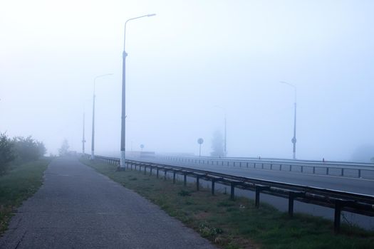 Bridge and road in the fog at dawn close up