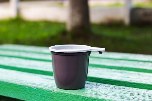 Plastic cup with coffee on a wooden bench close up