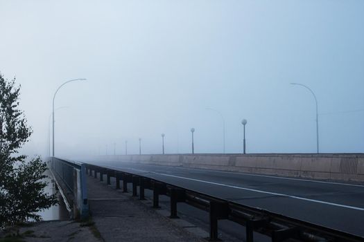 Bridge and road in the fog at dawn close up