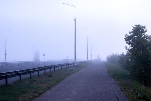 Bridge and road in the fog at dawn close up