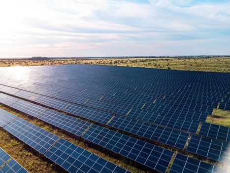 Aerial top view of a solar panels power plant. Photovoltaic solar panels at sunrise and sunset in countryside from above. Modern technology, climate care, earth saving, renewable energy concept