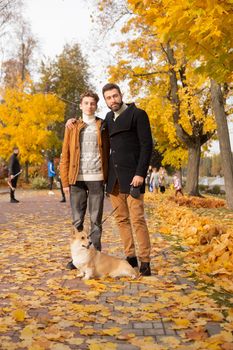 Father and son with a pet on a walk in the autumn park.