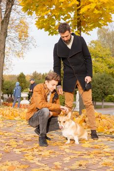 Father and son with a pet on a walk in the autumn park.