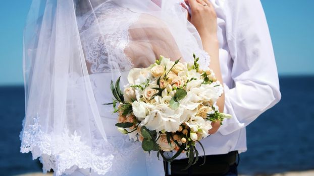 close-up of a wedding bouquet, amid hugs of newlyweds in wedding dresses. in the background sea and sky. High quality photo