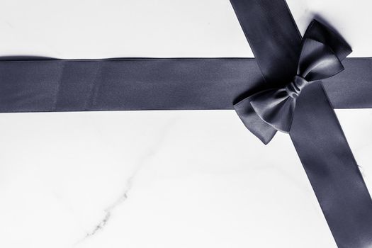 Holiday gift, decoration and sale promotion concept - Black silk ribbon and bow on marble background, flatlay