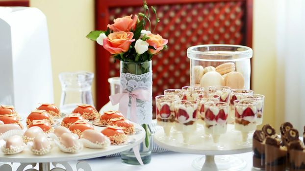 close-up, a variety of delicious desserts, cakes with cream, strawberries, chocolate, under icing , whipped cream, marshmallows, festive decor, sweet bar, corner, a treat. High quality photo