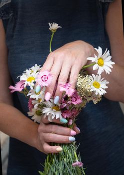 a young woman with a beautiful summer manicure holds a bouquet of wild flowers in pastel shades. High quality photo