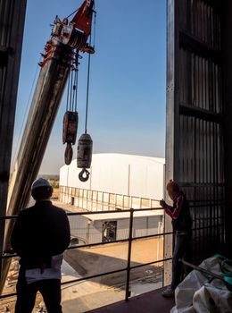 Hoist of crane at the window of industrial plant