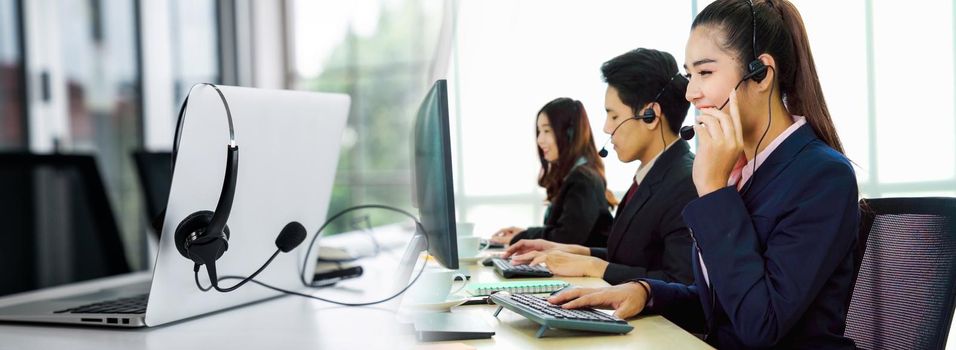 Business people wearing headset working in office in widen view to support remote customer or colleague. Call center, telemarketing, customer support agent provide service on telephone video call.