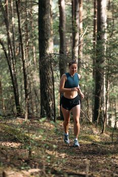 Fitness woman trail runner running in summer forest in the morning.