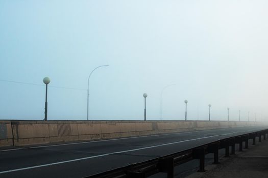Bridge and road in the fog at dawn close up